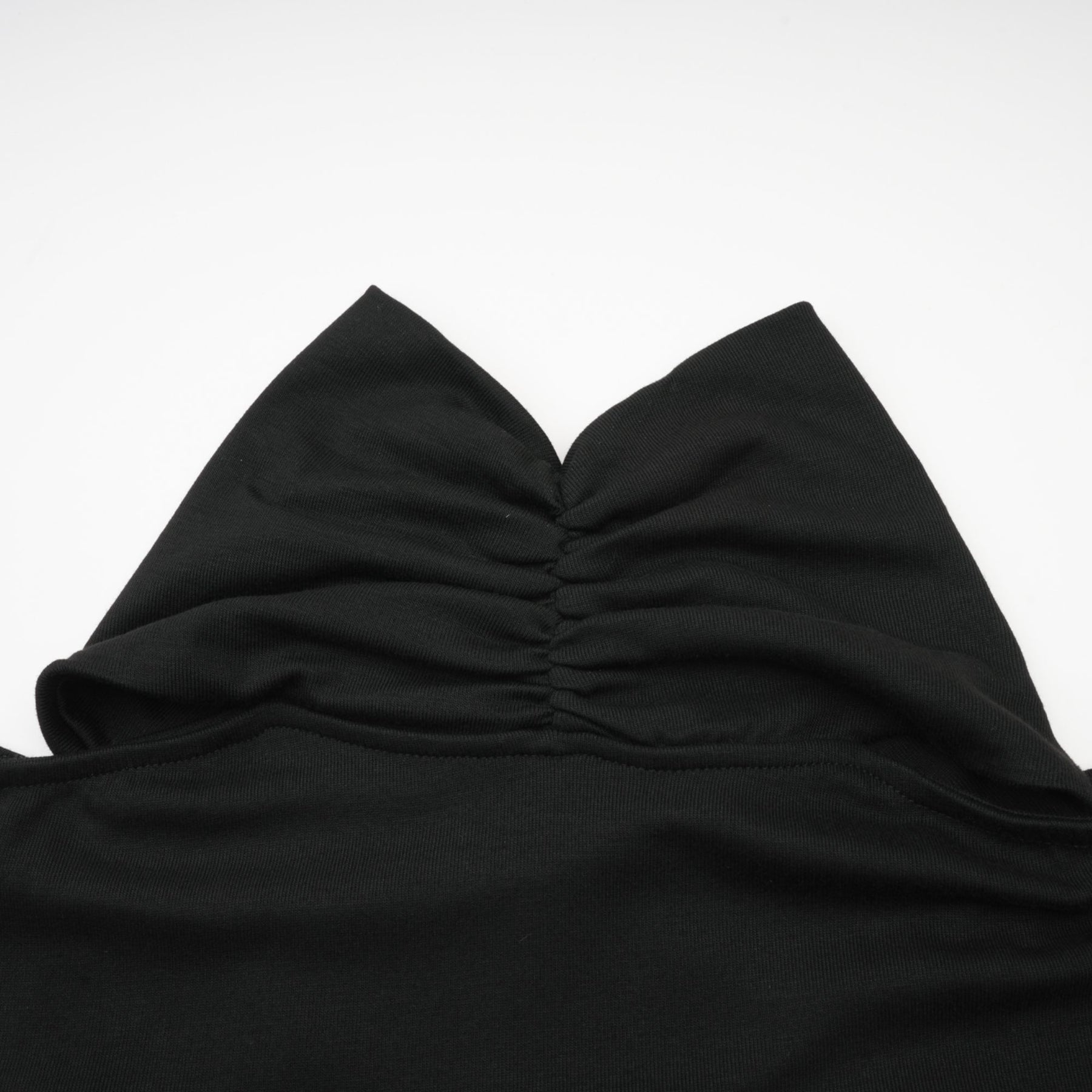 Woman wearing a black longsleeved top with ruched detailing made from stretchy jersey fabric