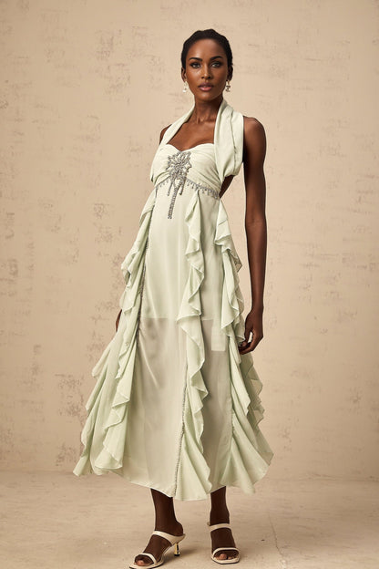 A woman wearing a midilength dress with ruffled details and embellishments named Salilah
