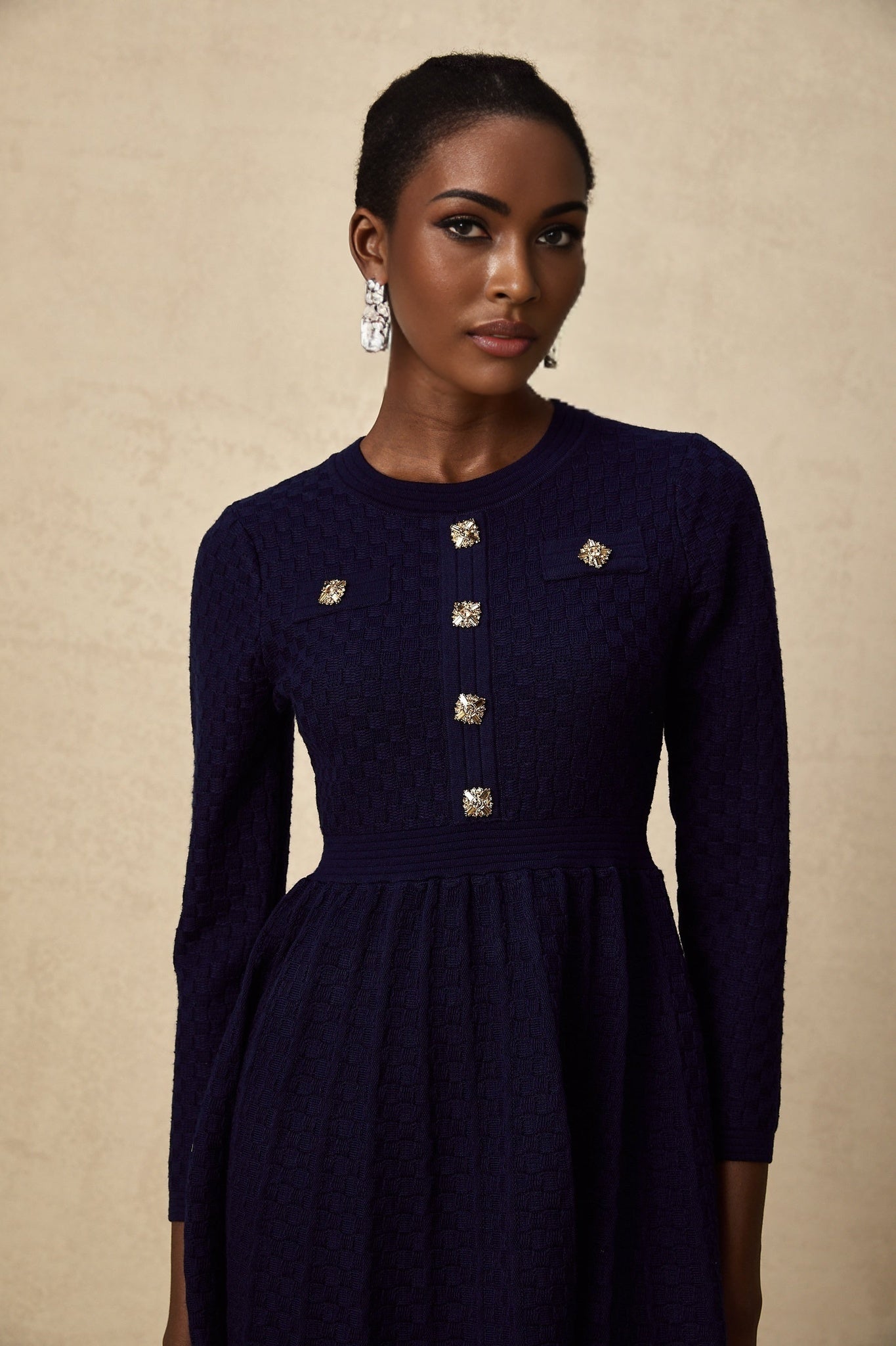 Woman wearing a navy blue mini dress with basket weave texture short sleeves and fitted silhouette