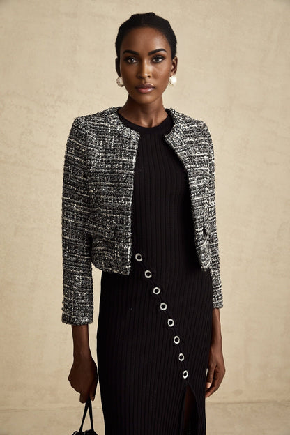 Woman wearing black bouclé tweed jacket with textured fabric and classic tailored design