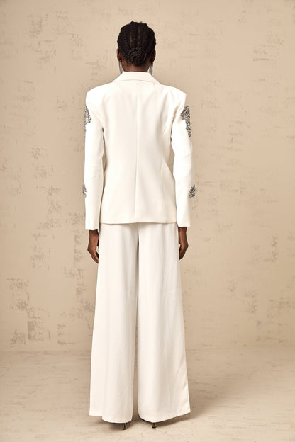 Woman wearing white blazer and trousers set embellished with crystal details