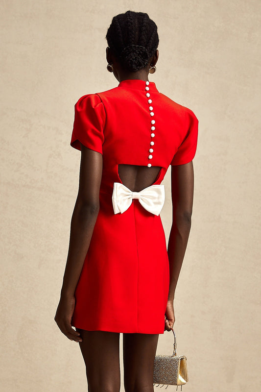 Young woman wearing a short red dress with petal sleeves and a cutout detail with bow accent